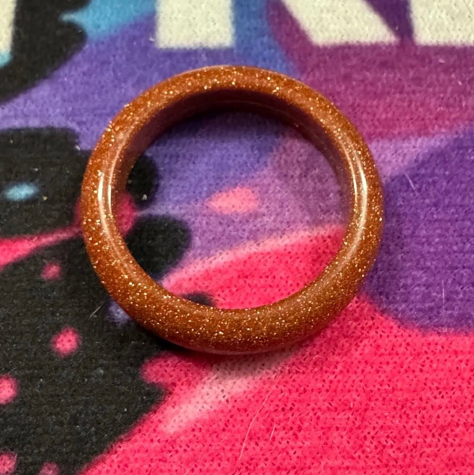 Brown glittery ring on a colorful fabric background