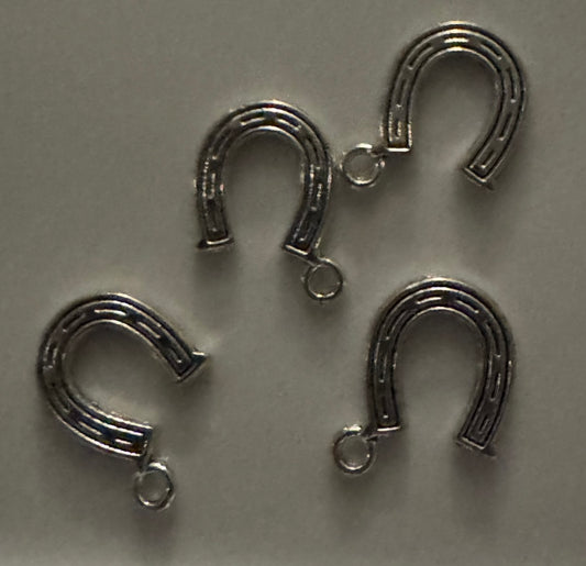 Five silver horseshoe-shaped jewelry charms with attached jump rings, arranged on a plain light gray background.