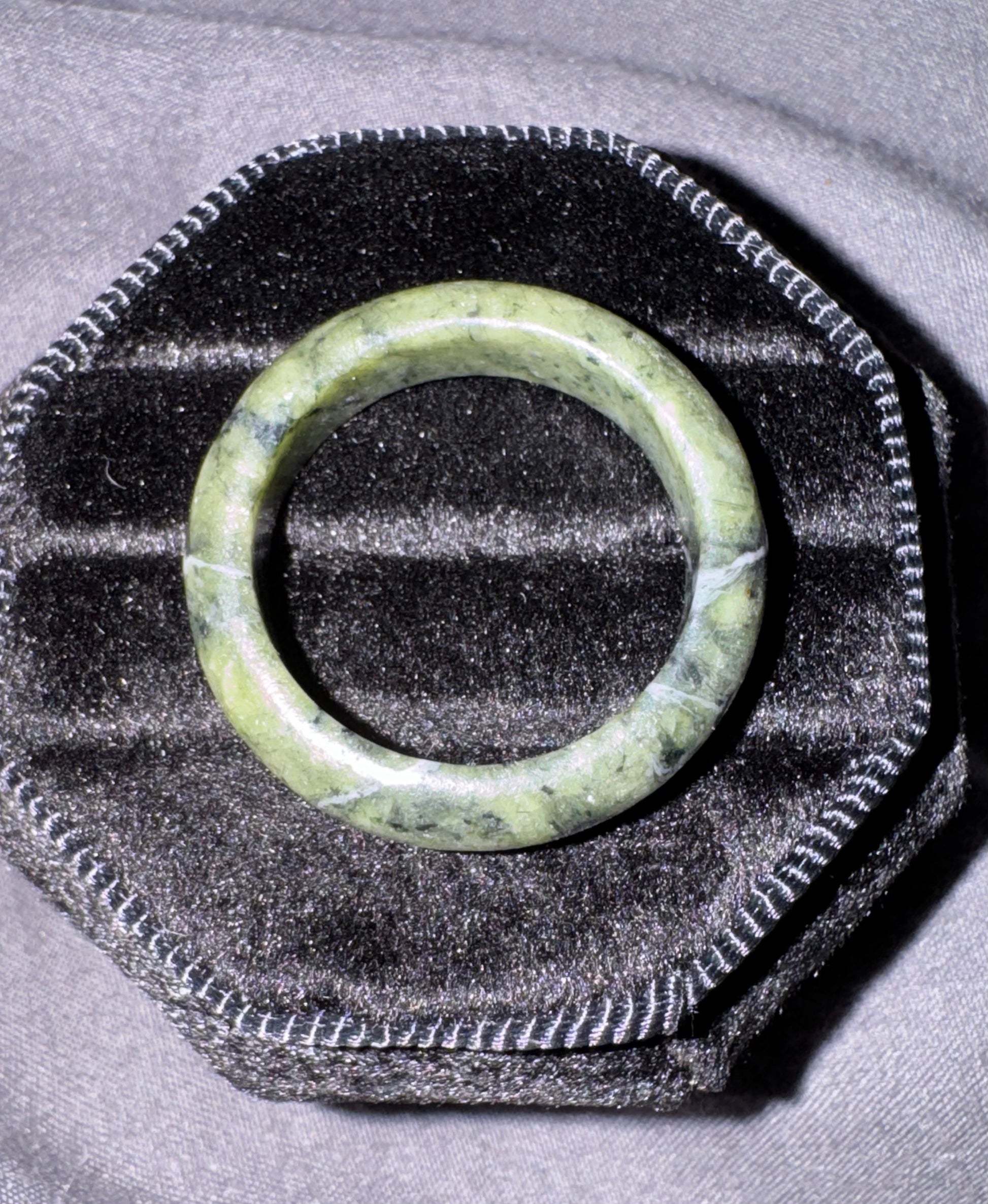 Green jade ring on a textured black and gray surface
