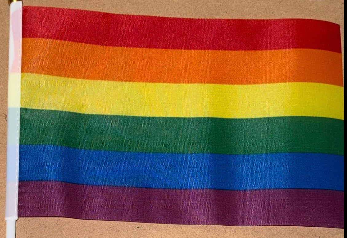 Rainbow flag with red, orange, yellow, green, blue, and purple stripes on a beige background