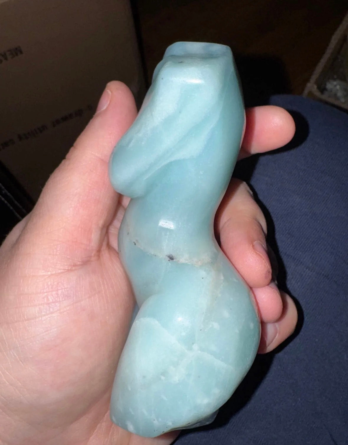 Light blue ceramic object held in a hand against a dark background