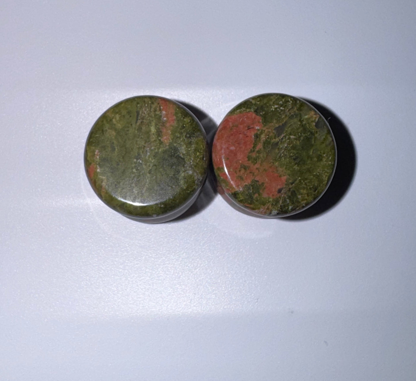 Two Unakite ear gauges on a white background