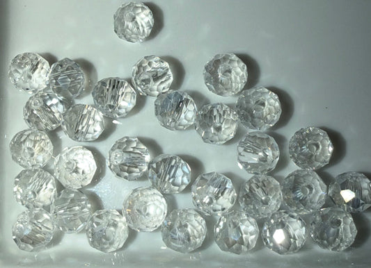 A group of clear, faceted round beads scattered on a light gray background.