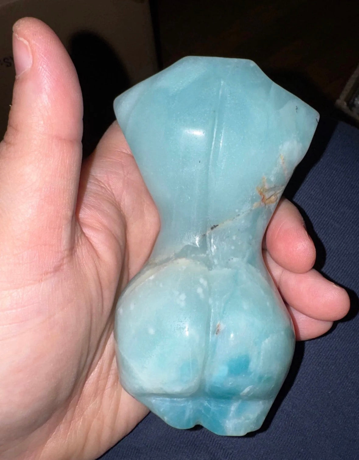 Hand holding a blue stone with a dark background