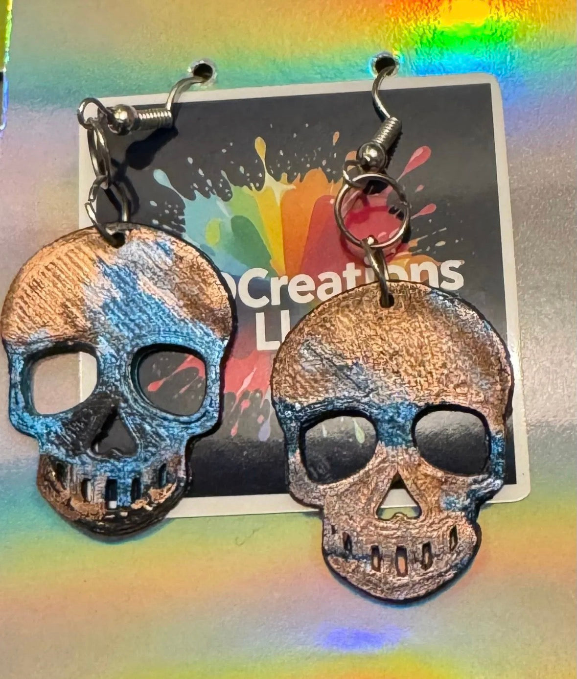 Blue and Copper Skull-shaped earrings on a colorful card.