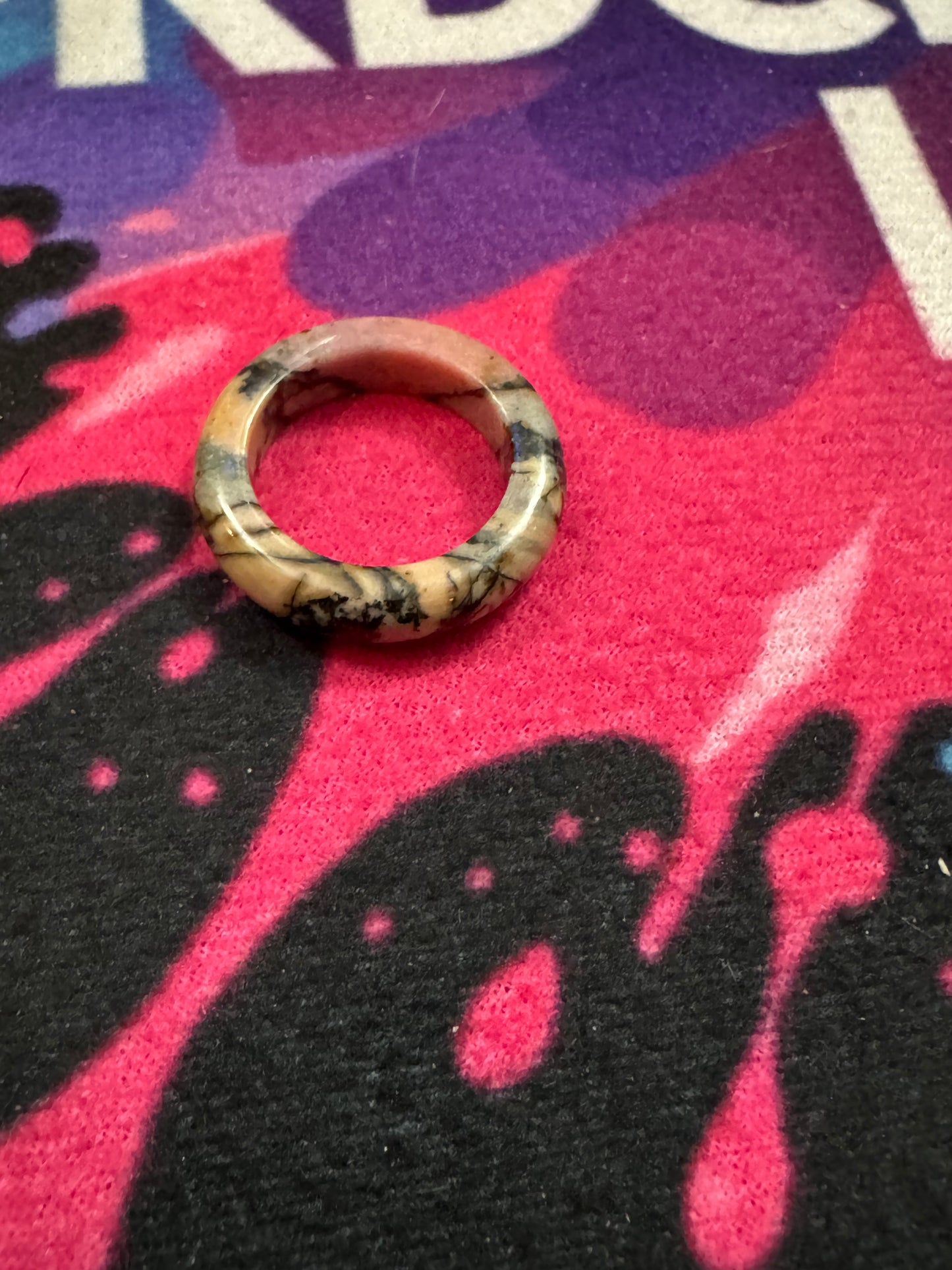 Rhodonite ring on a colorful fabric background