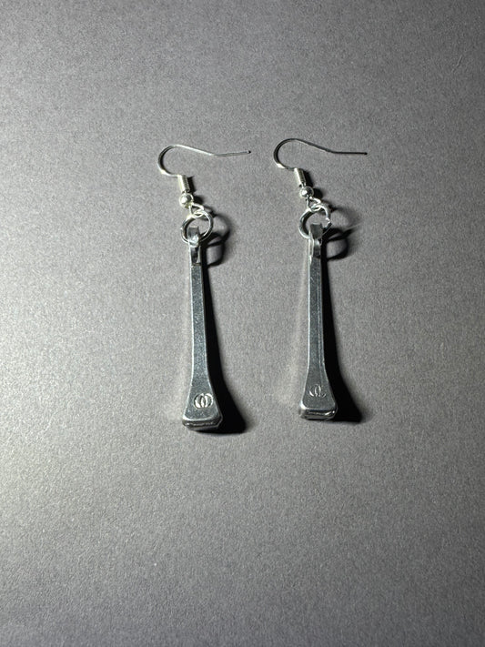 A pair of silver-toned drop earrings with elongated rectangular pendants and fishhook ear wires, photographed on a plain gray surface.