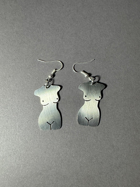 A pair of silver dangle earrings shaped like stylized female torso silhouettes, shown on a plain gray background.
