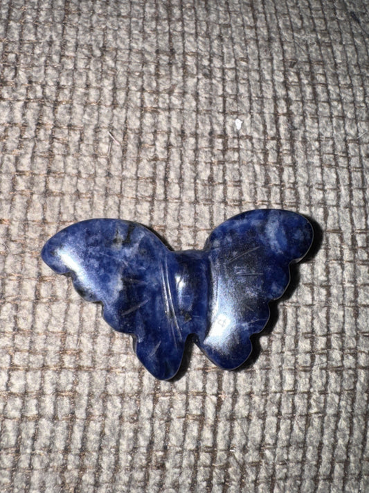 Blue butterfly-shaped object on a textured beige surface