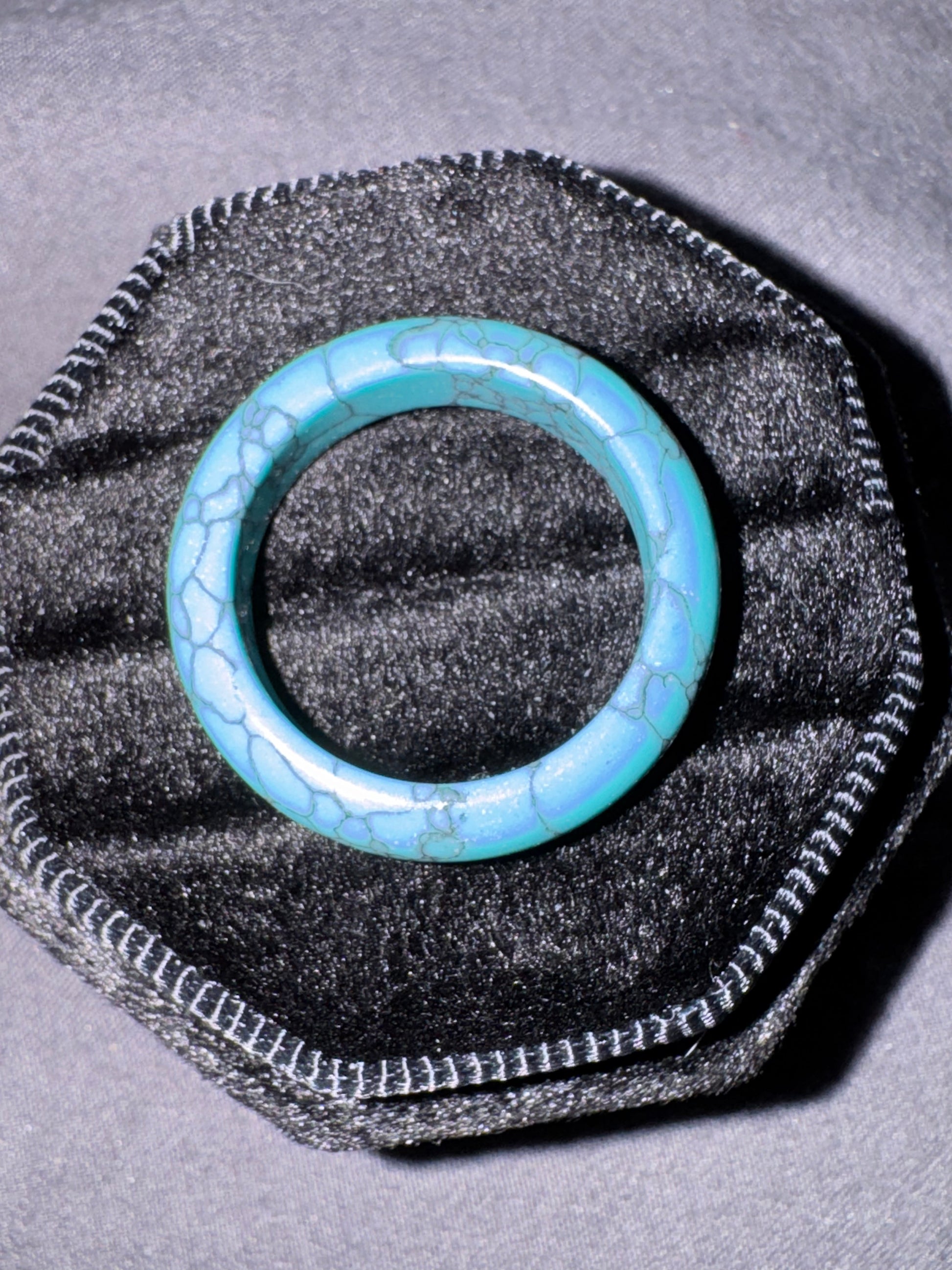 Turquoise ring on a black textured stand