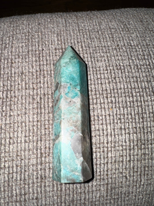 Turquoise crystal point on a textured gray surface