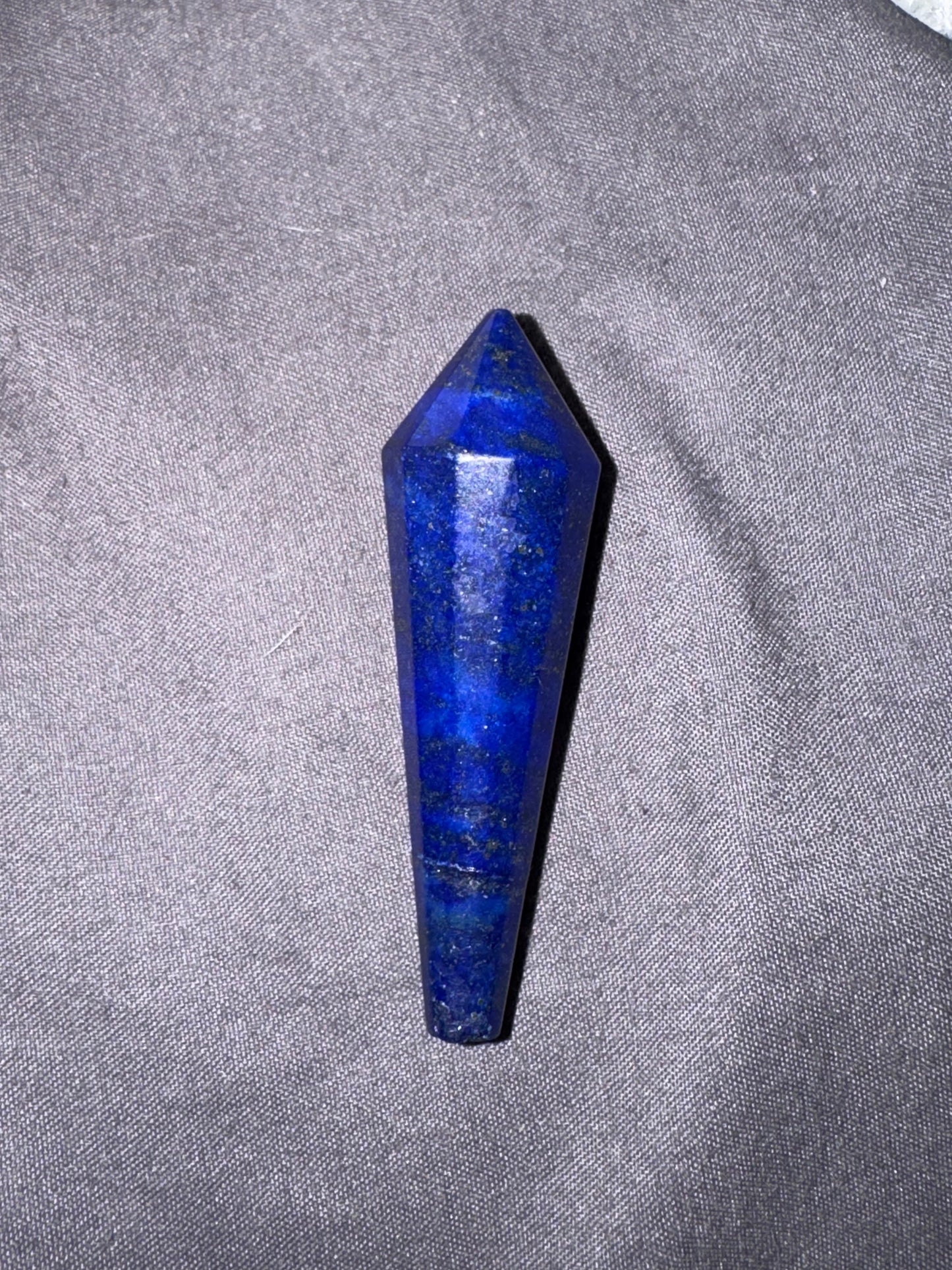 Blue crystal pendulum on a gray fabric background