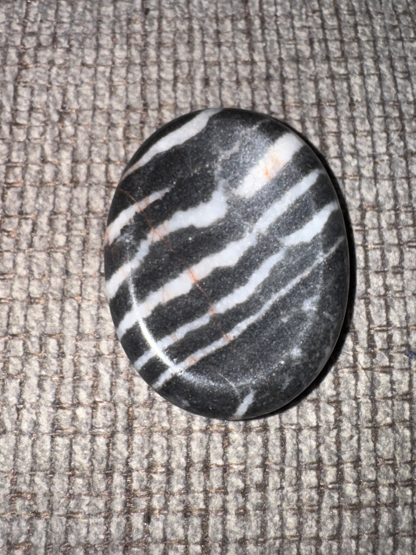 Black and white striped stone on a textured gray surface