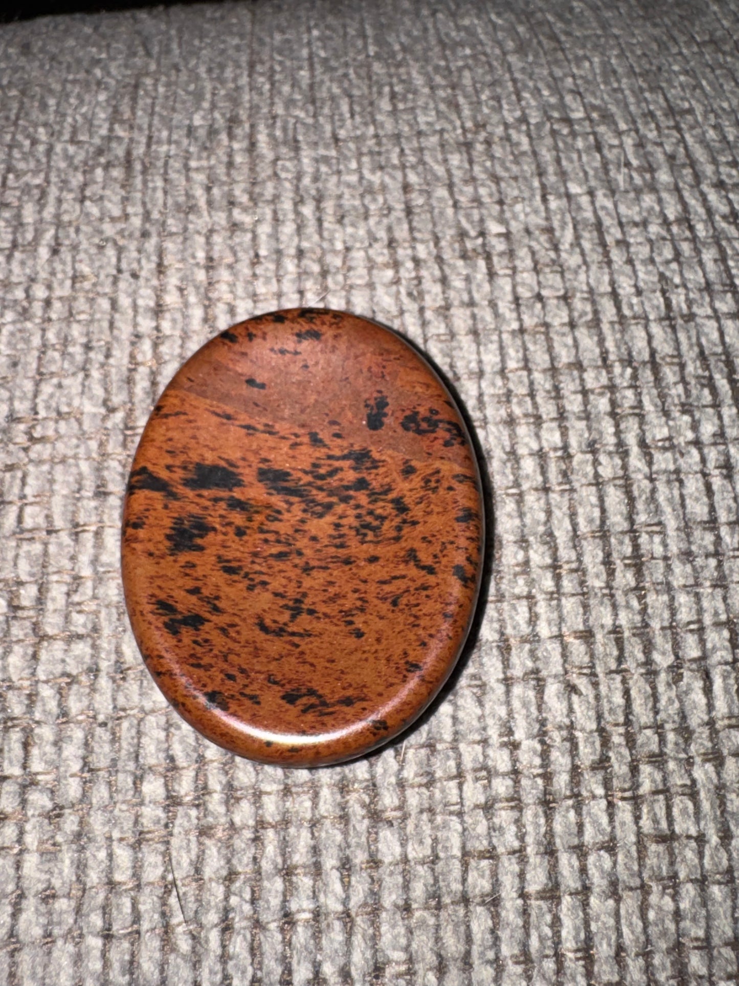 Brown speckled stone on a textured gray surface