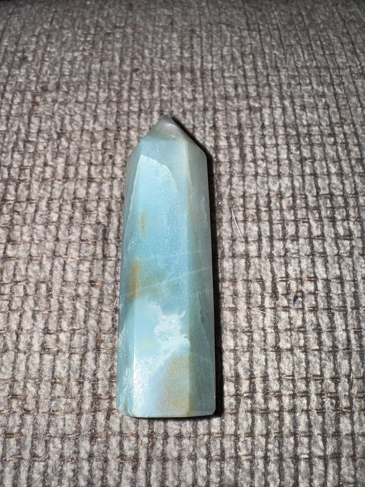 Blue-green crystal on a textured gray surface