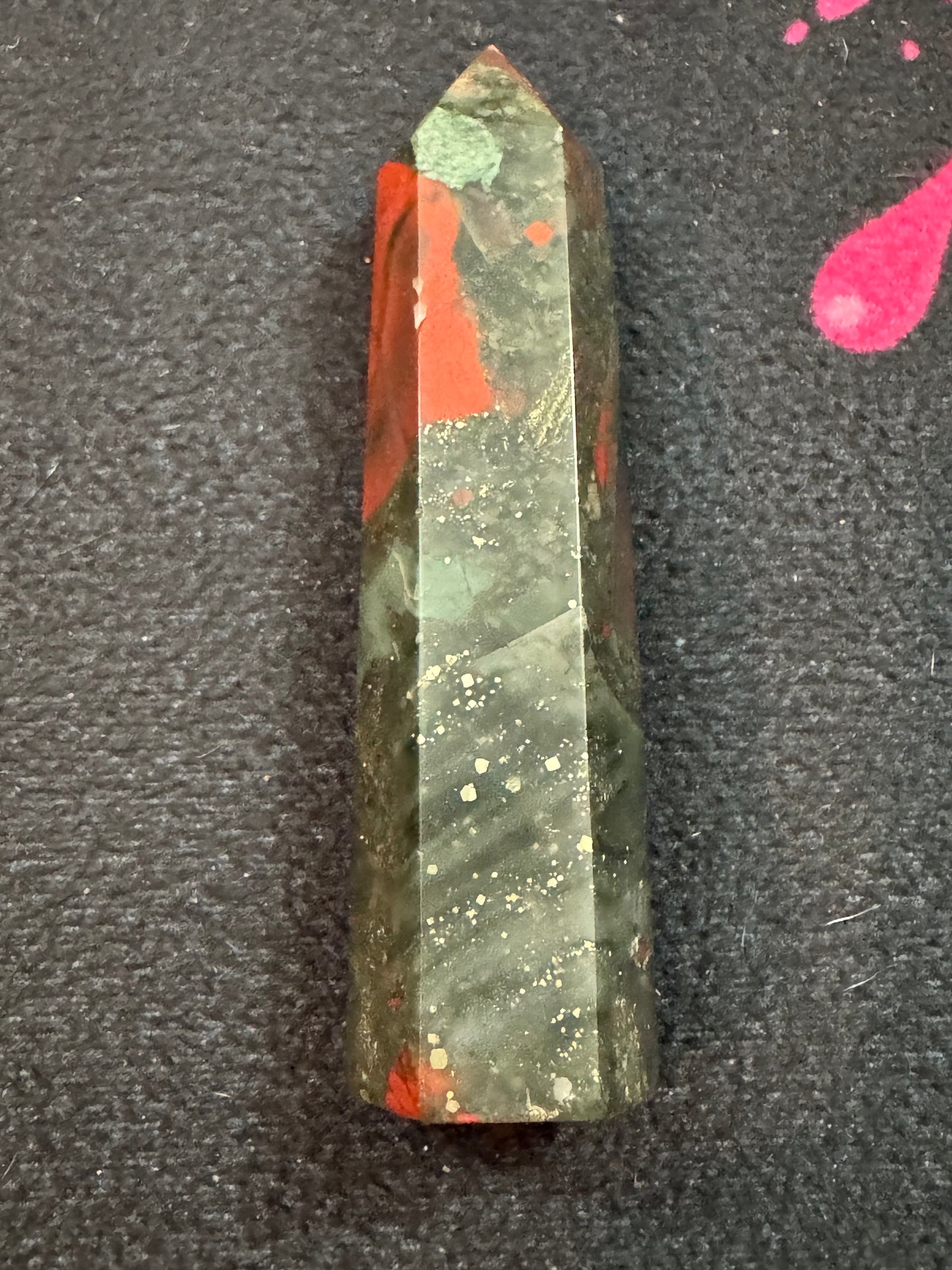 Green and red crystal on a dark textured surface