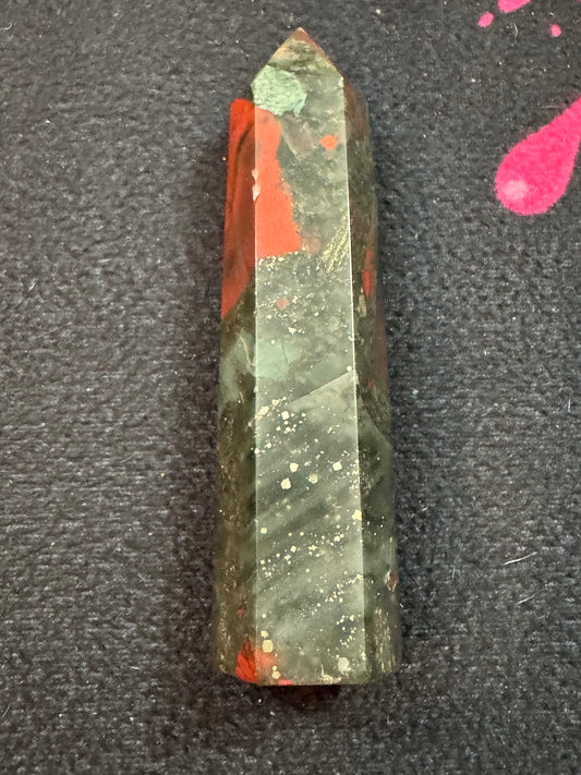 Green and red crystal on a dark textured surface