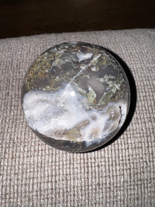 Moss agate sphere on a textured surface
