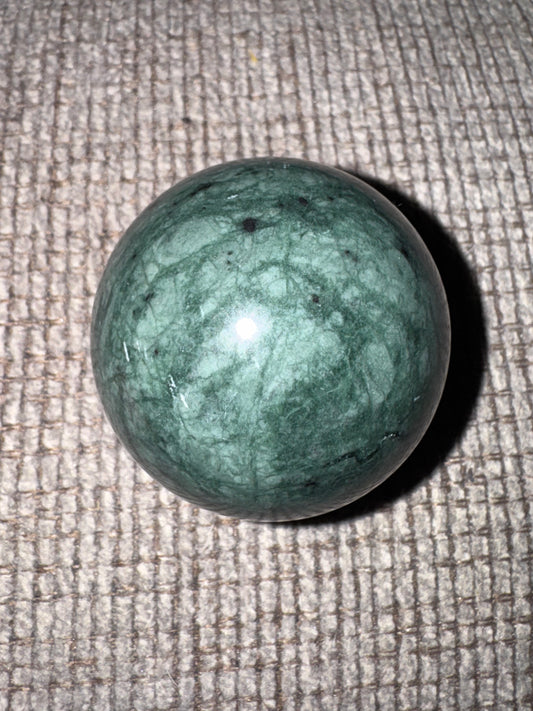 Jadite sphere on a textured beige surface