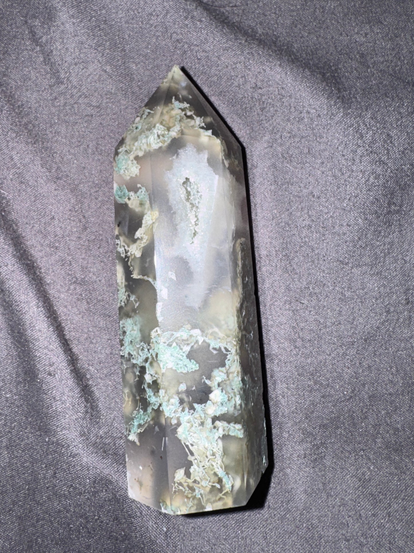 Crystal tower with green and white markings on a gray fabric background