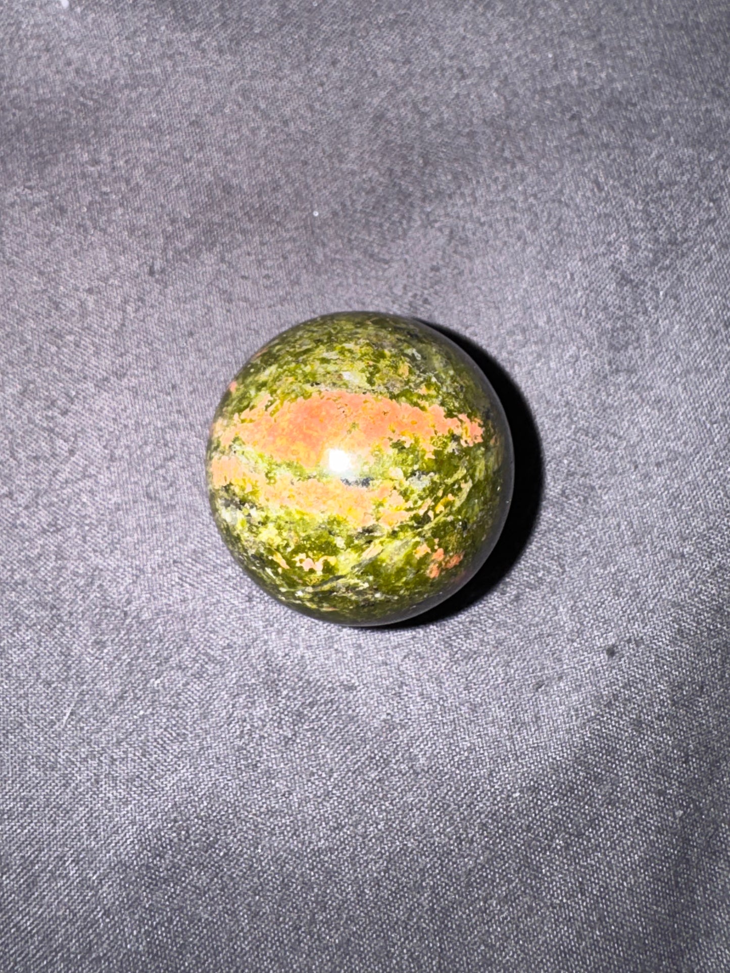 Round green stone with orange center on a gray textured surface