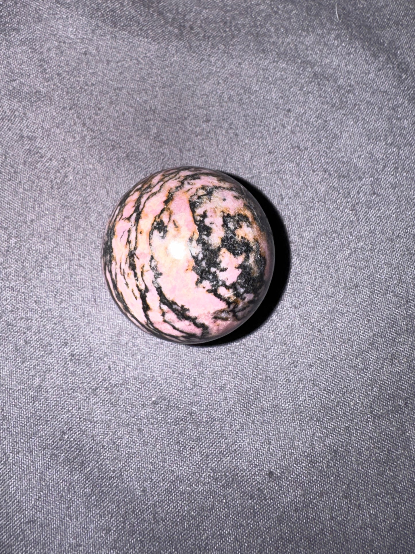 Marbled pink and black stone on a gray fabric background