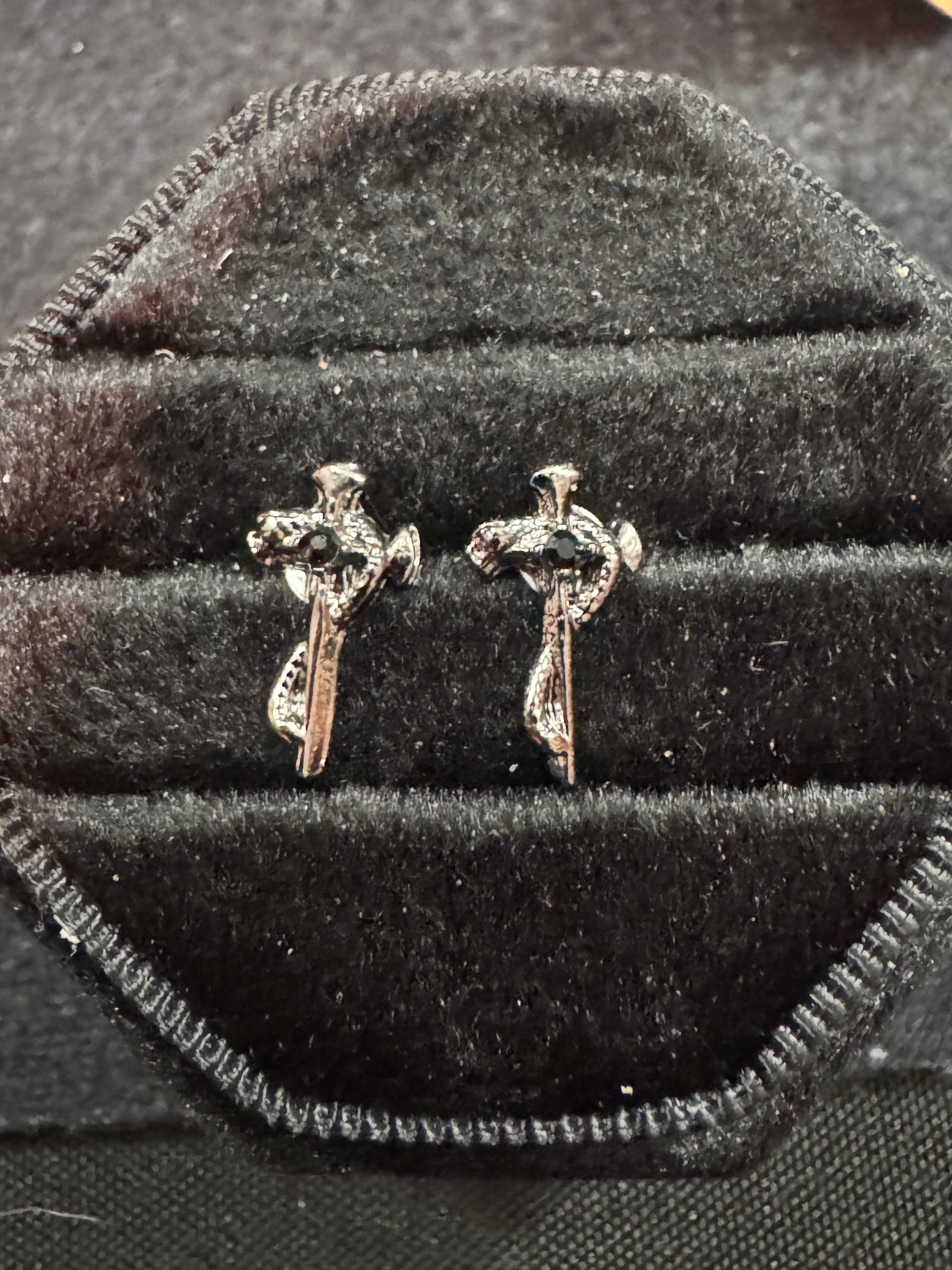 Pair of silver cross earrings on a black velvet surface