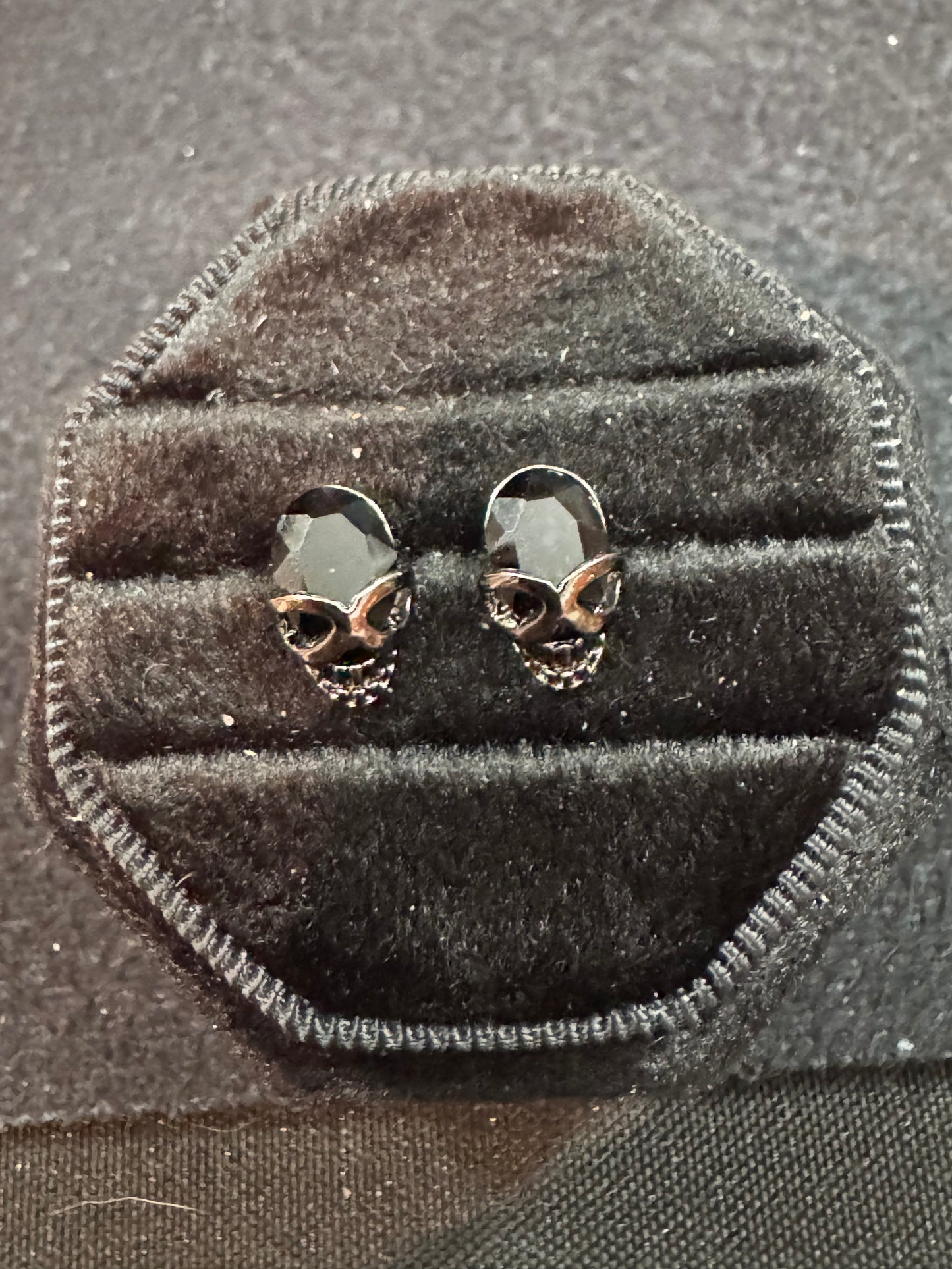 Skull-shaped earrings in a black velvet display box