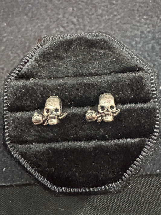 Skull-shaped earrings on a black velvet cushion