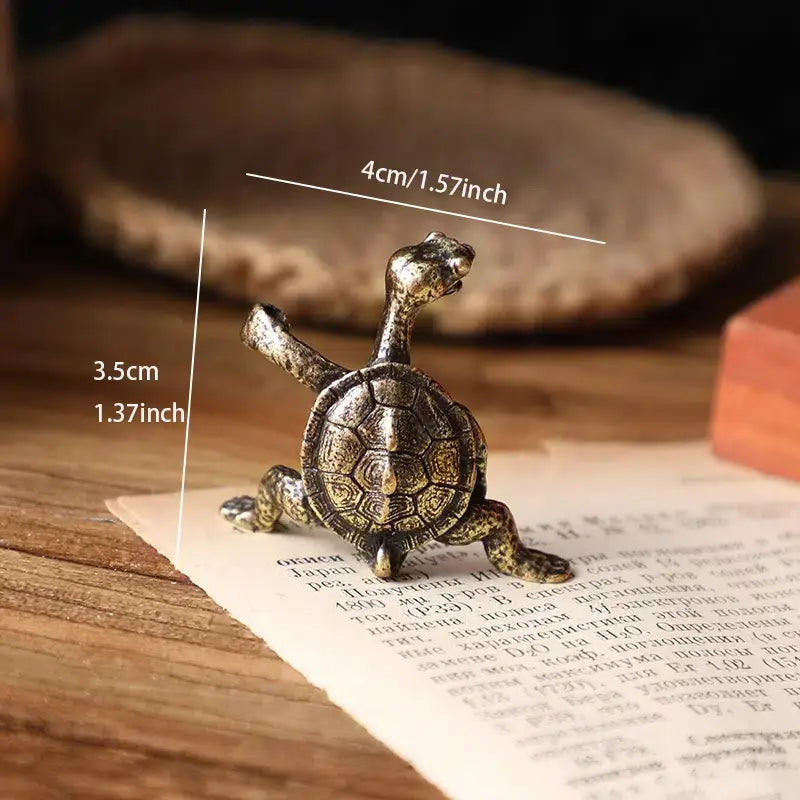 Bronze turtle figurine with measurements on a wooden surface